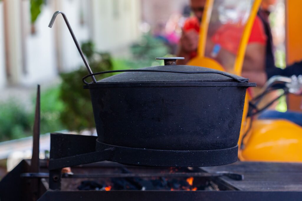 Un grand pot noir sur une flamme ouverte, parfait pour la cuisine en extérieur ou les scènes de camping.