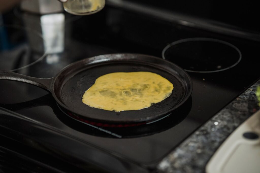 Gros plan sur des œufs brouillés cuisant dans une poêle sur une cuisinière à induction.