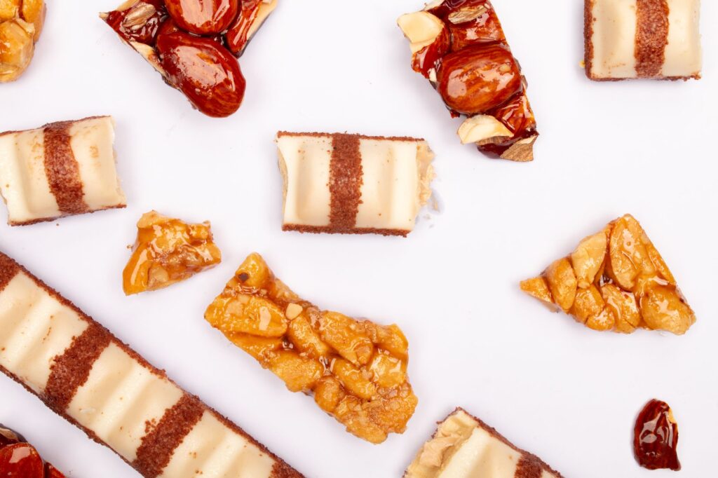 Gros plan de noix et bonbons sucrés disposés sur une surface blanche, idéal pour la photographie culinaire.
