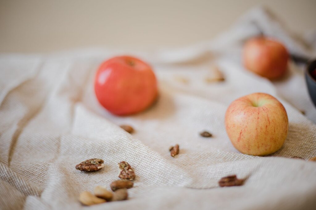 Gros plan sur des pommes et des noix sur un tissu текстuré, mettant en avant les aliments sains et biologiques.