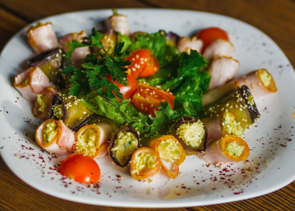 Des rouleaux colorés de légumes et de jambon, garnis de tomates cerises et de laitue, parfaits pour un repas sain.