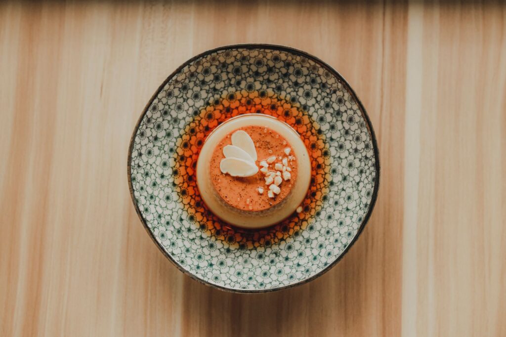 Un dessert flan magnifiquement présenté servi sur une assiette décorative avec un fond en bois.