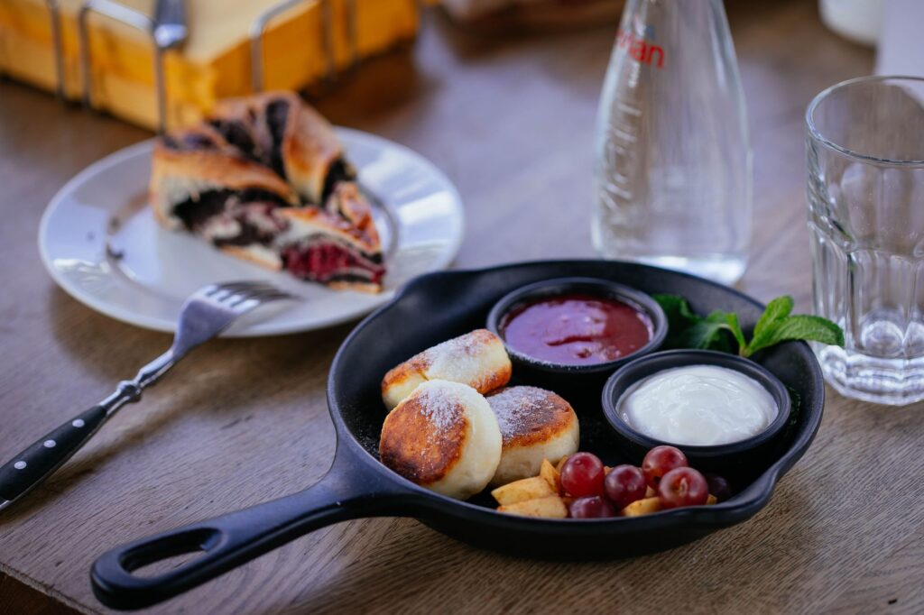 Savourez un petit déjeuner savoureux avec des syrniki, des raisins frais et un dessert aux baies dans un cadre cosy.