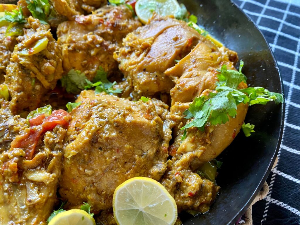 Gros plan sur un plat de poulet épicé savoureux garni de tranches de citron et d'herbes fraîches.