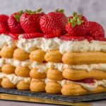 Un délicieux dessert en couches avec des fraises fraîches, de la crème et du gâteau éponge sur un plateau en ardoise.