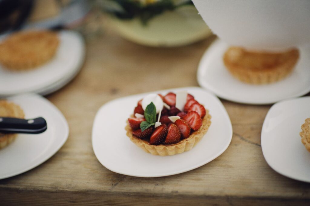 Tarte aux fraises fraîches avec des feuilles de menthe sur une assiette blanche, parfaite pour les amateurs de desserts.