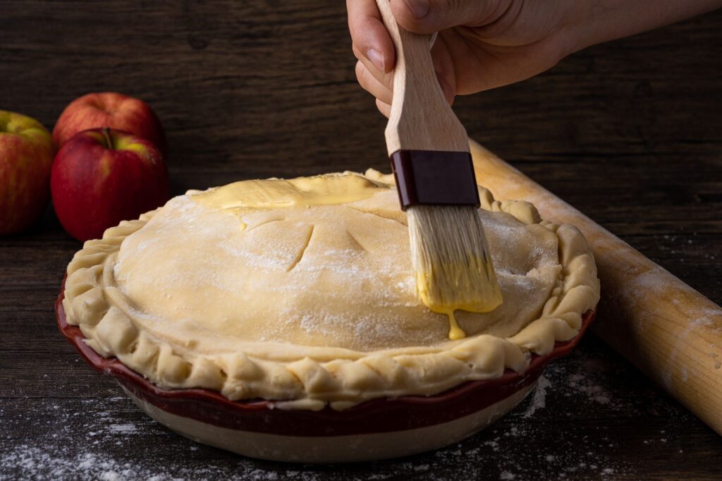 Un gros plan d'une tarte aux pommes faite maison préparée avec un bain d'œuf sur une surface en bois.