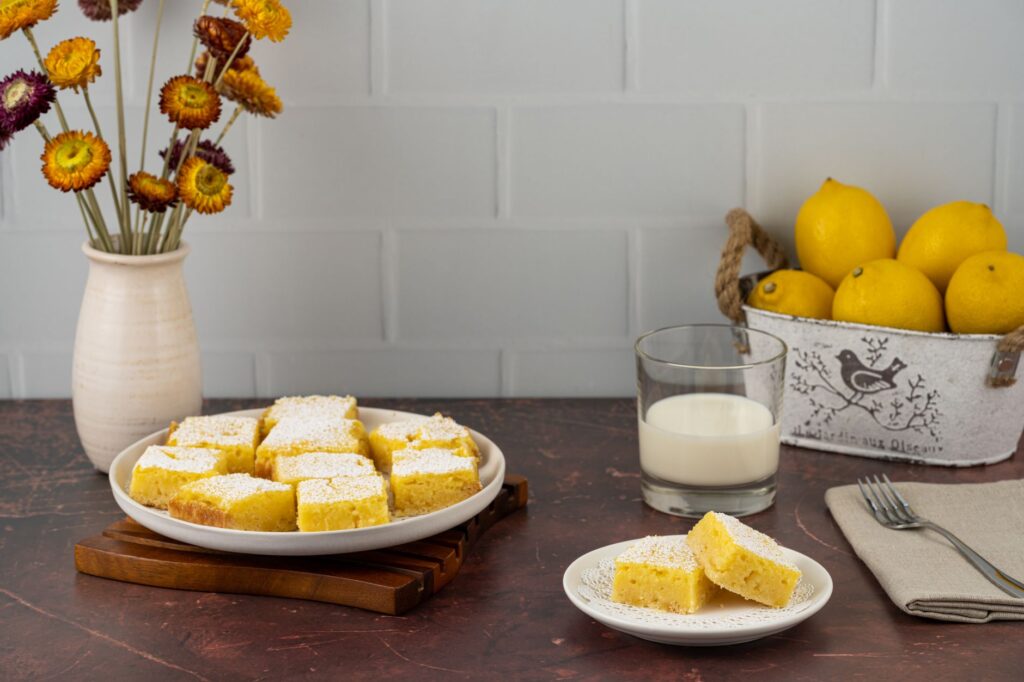 Délicieuses barres au citron faites maison avec un verre de lait sur une table rustique.
