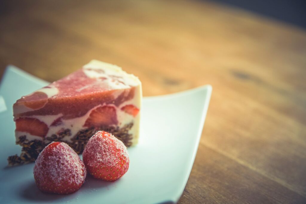 Une délicieuse part de gâteau à la crème de fraise avec des fraises fraîches sur une assiette moderne blanche.