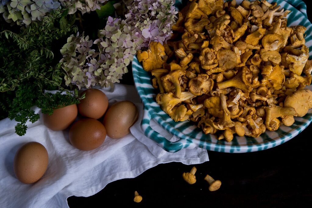 Une composition rustique de champignons chanterelles, d'œufs et d'herbes fraîches sur une assiette en céramique.
