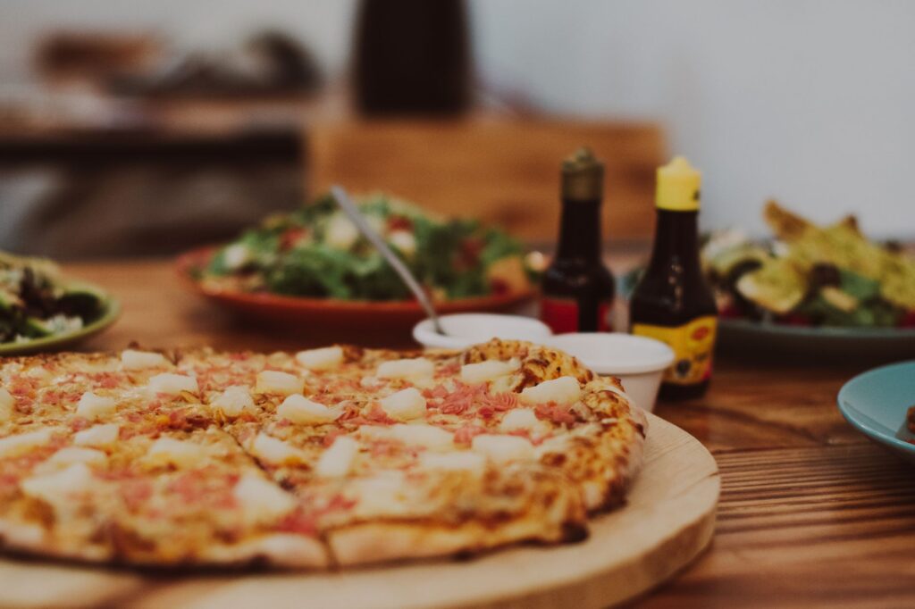 Gros plan sur une délicieuse pizza hawaïenne avec des toppings d'ananas et de jambon sur une table en bois.