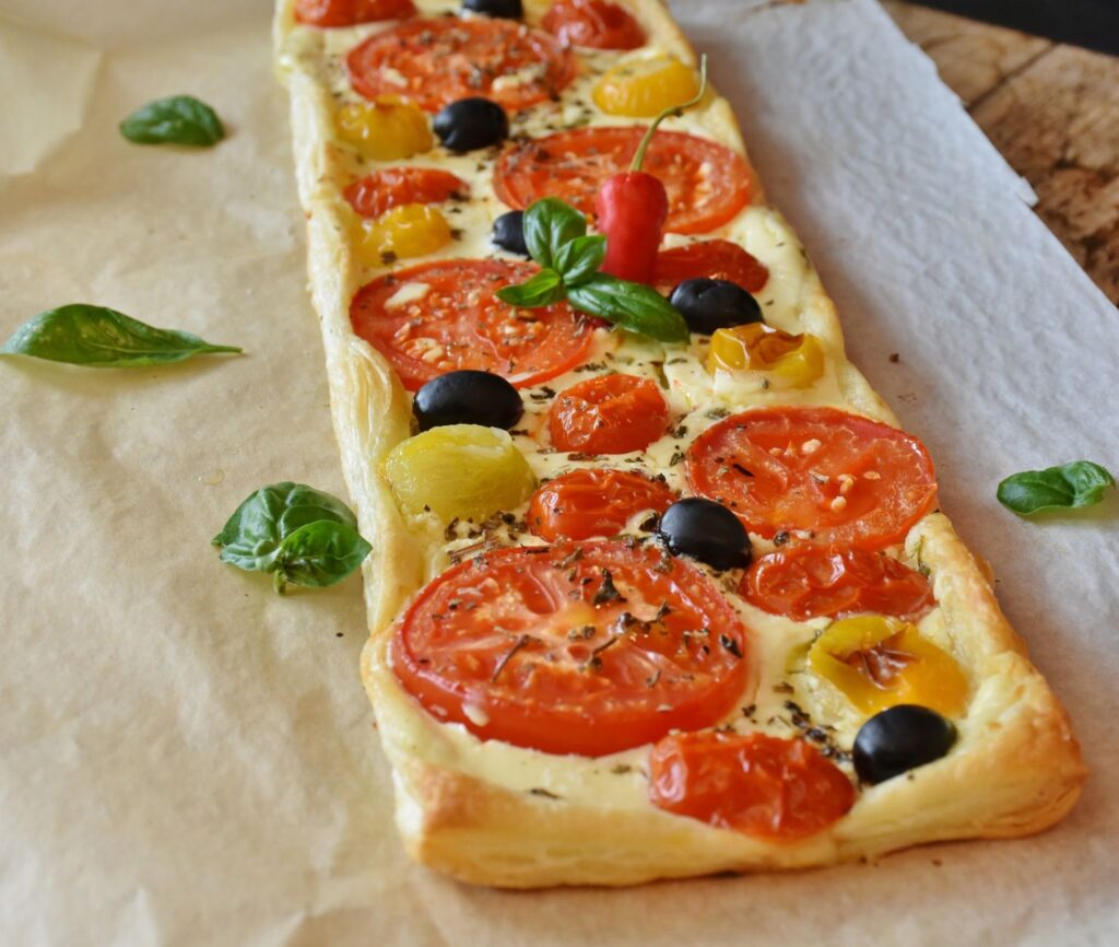 Délicieuse tarte végétarienne garnie de tomates fraîches, d'olives et de basilic. Parfaite pour un repas savoureux.