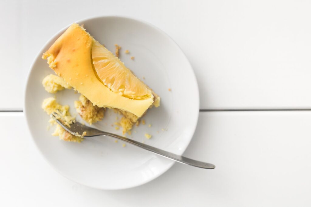 Délicieuse part de cheesecake garnie d'ananas, servie sur une assiette blanche.