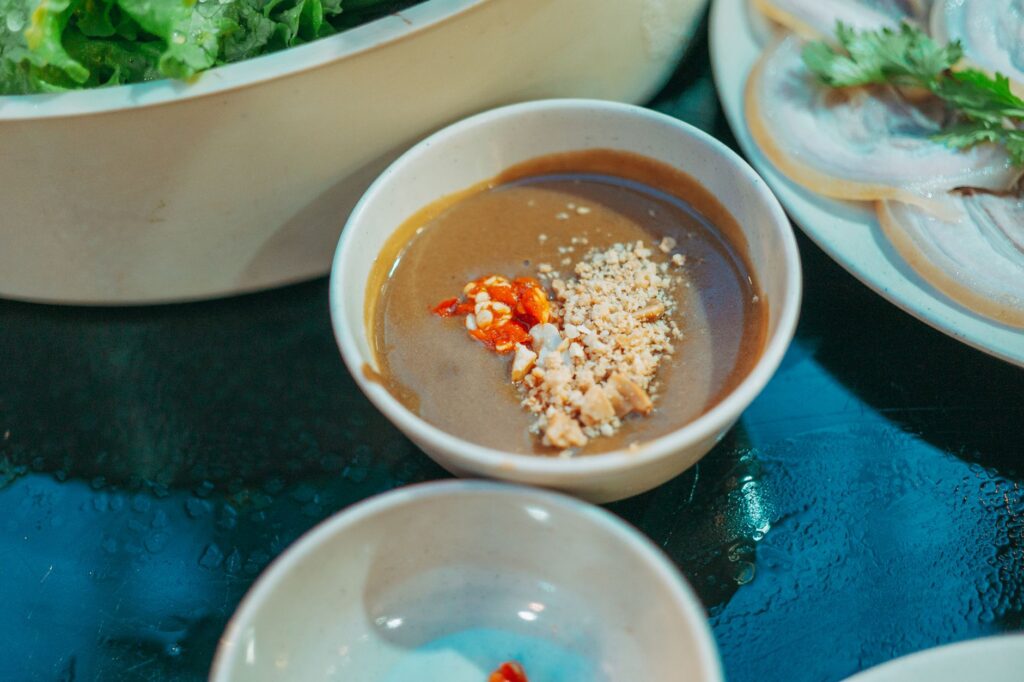 Un gros plan vibrant d'une sauce d'accompagnement asiatique traditionnelle garnie de cacahuètes.