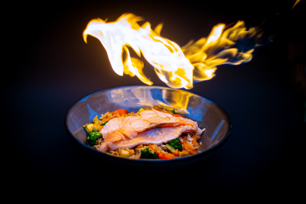 Saumon grillé vibrant servi sur du riz frit aux légumes, sur un fond noir saisissant.