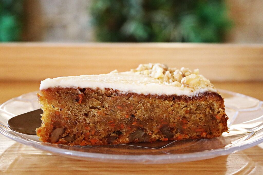 Une délicieuse part de gâteau à la carotte avec un glaçage au fromage à la crème, parfaite pour les amateurs de desserts.