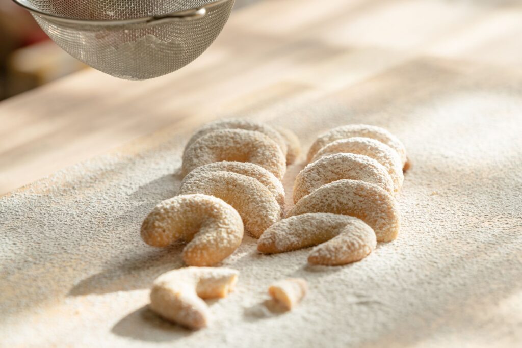 Gros plan de biscuits Kipferl à la vanille faits maison, saupoudrés de sucre glace, mettant en valeur leur attrait délicieux.