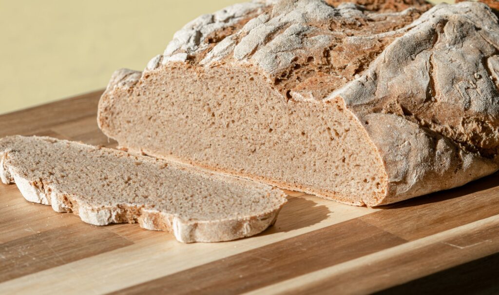 Gros plan de pain de seigle rustique fraîchement cuit sur une planche à découper en bois, parfait pour la photographie culinaire.