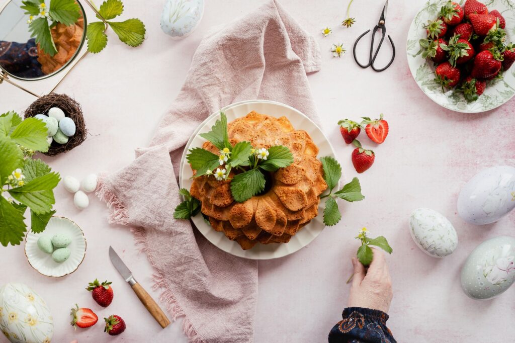 Charmant gâteau bundt entouré de fraises fraîches et d'œufs de Pâques. Parfait pour les festivités de printemps.