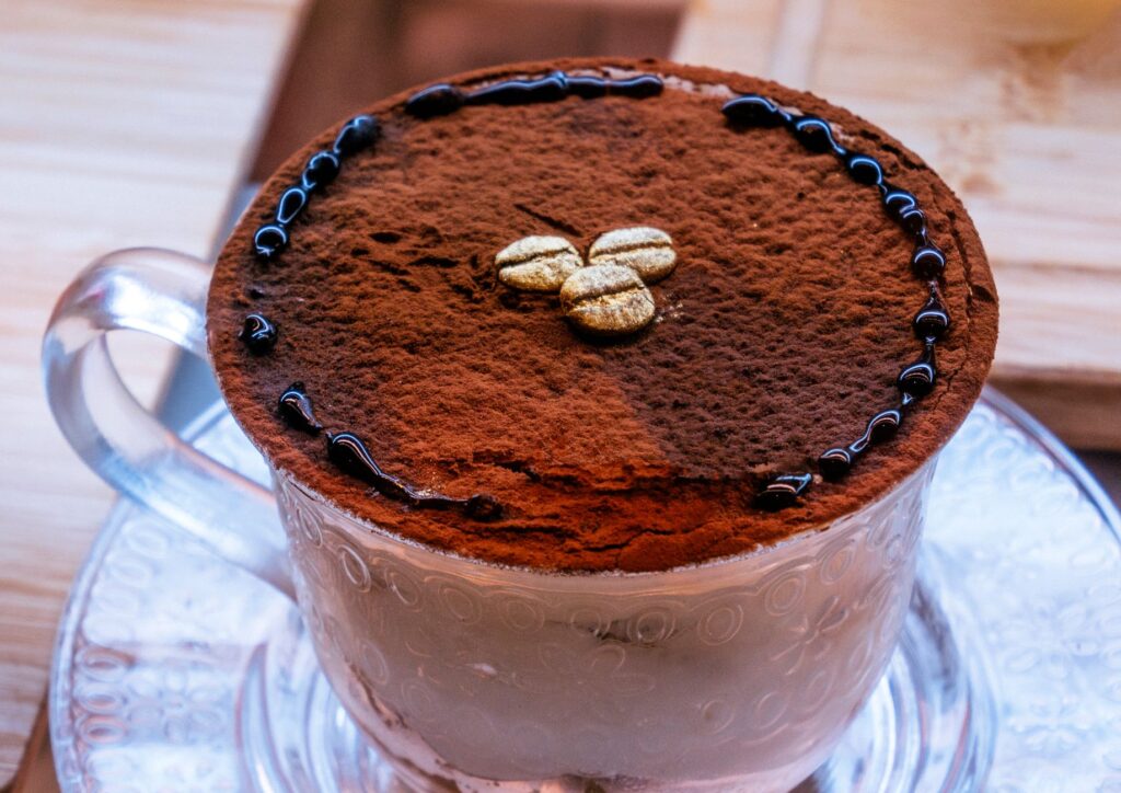 Gros plan sur un cappuccino riche, saupoudré de cacao et d'éléments décoratifs, servi à l'intérieur.