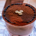 Gros plan sur un cappuccino riche, saupoudré de cacao et d'éléments décoratifs, servi à l'intérieur.