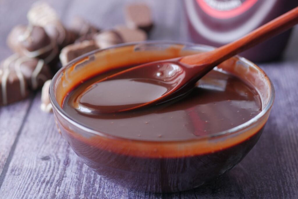 Gros plan sur du chocolat fondu dans un bol en verre, idéal pour la pâtisserie ou les garnitures de dessert.