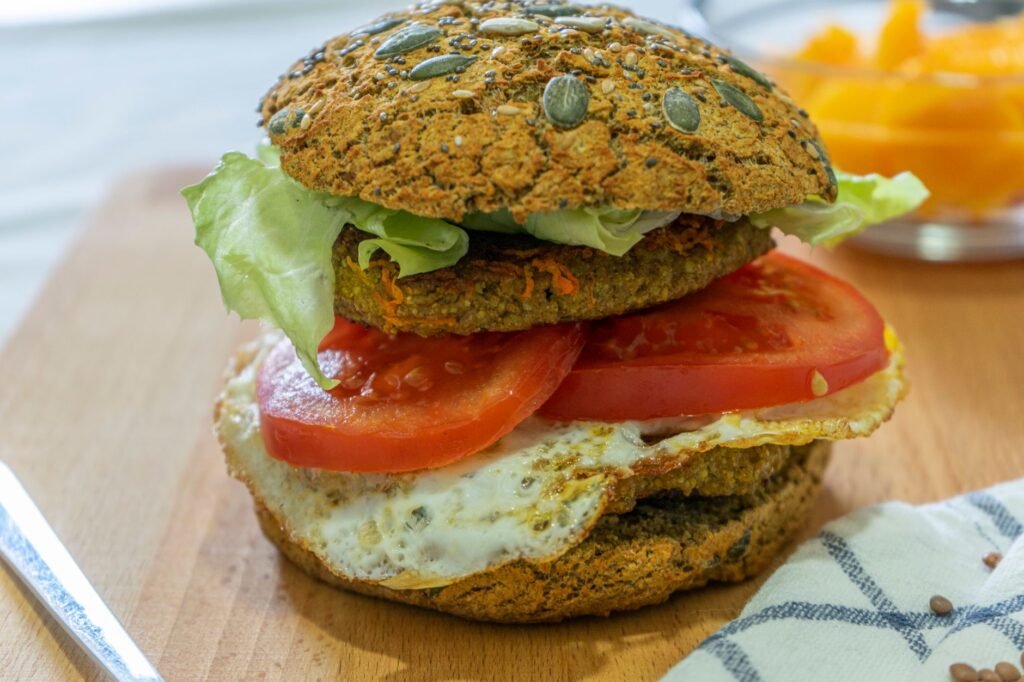 Gros plan d'un délicieux burger végétalien avec de la laitue fraîche et des tomates sur un pain à semences, parfait pour un repas sain.