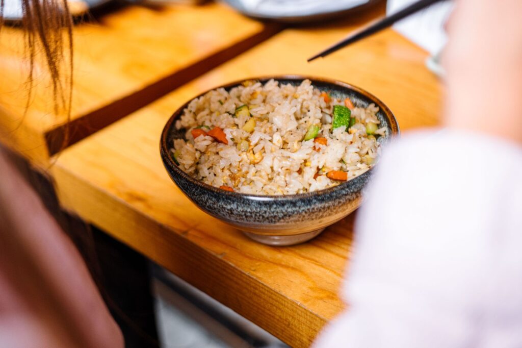 Un gros plan d'un délicieux bol de riz frit aux légumes sur une table en bois.