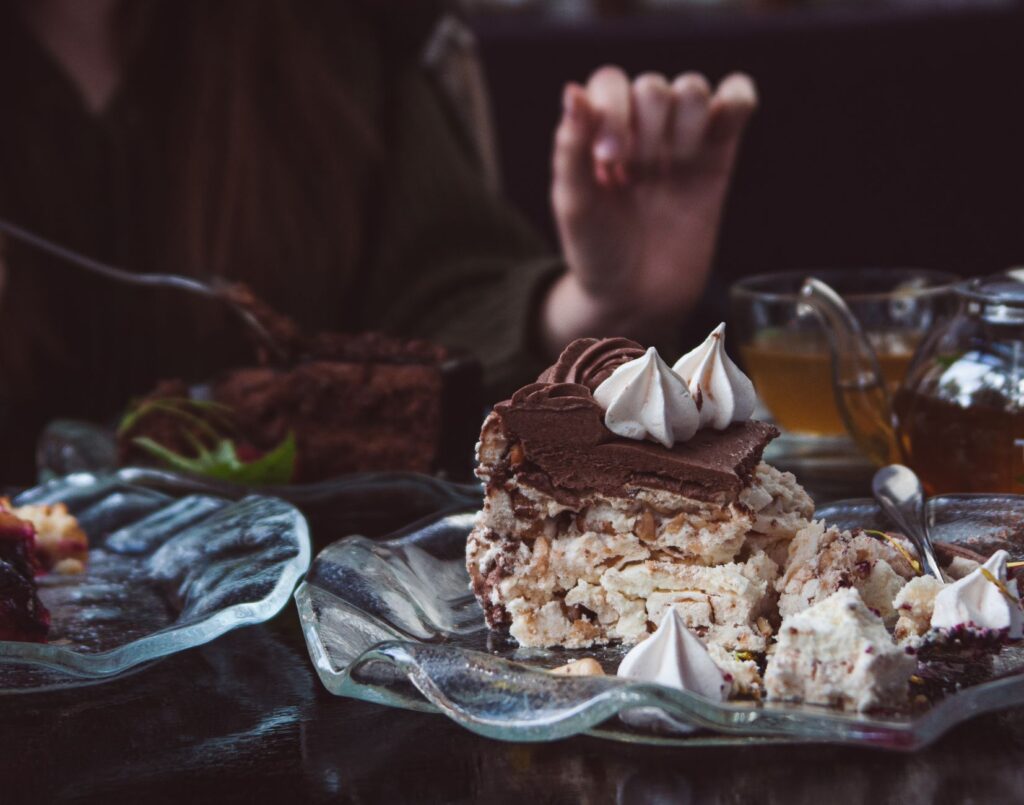 Gros plan sur une tranche de gâteau au chocolat décadent avec une garniture de meringue sur une assiette en verre, parfait pour les amateurs de desserts.