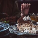 Gros plan sur une tranche de gâteau au chocolat décadent avec une garniture de meringue sur une assiette en verre, parfait pour les amateurs de desserts.
