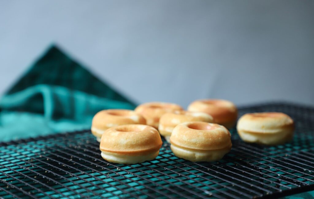 Mini beignets fraîchement cuits empilés sur une grille de refroidissement, capturés à l'intérieur sous une lumière douce.