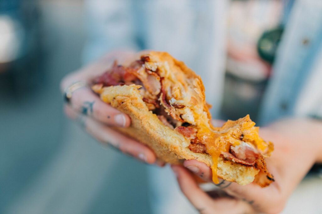 Délicieux sandwich avec du bacon et un œuf, avec du fromage fondu à la main, parfait pour les amateurs de nourriture.