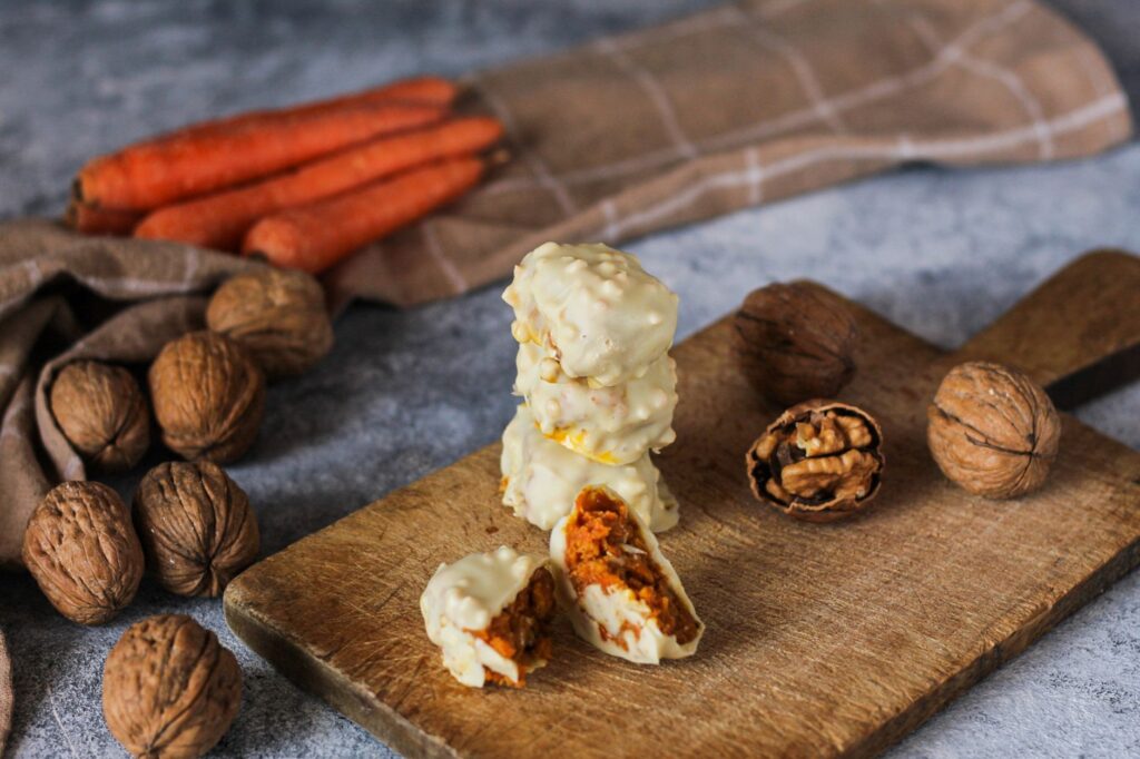Délicieuses sucreries à la carotte au chocolat blanc sur une planche en bois rustique avec des noix.