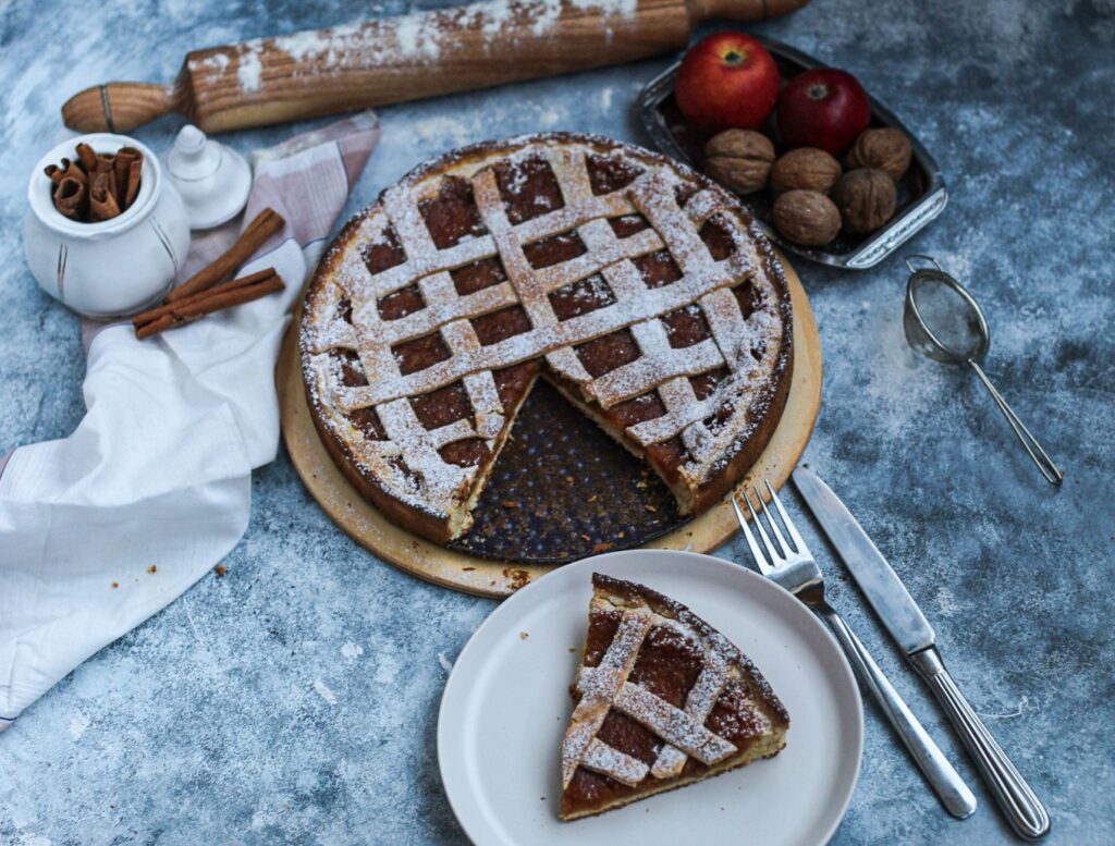 Tarte aux pommes maison avec de la cannelle et des noix sur une table rustique.
