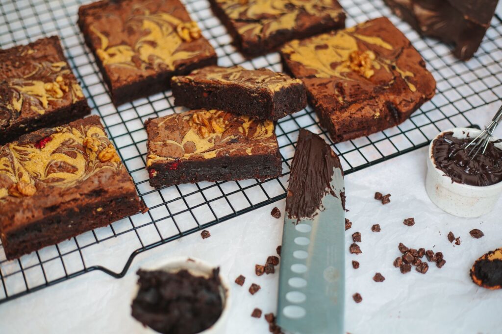 Gros plan sur des brownies au chocolat riches avec des noix et un design marbré, tranchés sur une grille de refroidissement.