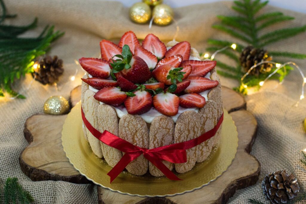 Délicieux gâteau charlotte orné de fraises fraîches et de décorations festives, parfait pour les célébrations de Noël.