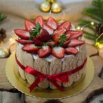 Délicieux gâteau charlotte orné de fraises fraîches et de décorations festives, parfait pour les célébrations de Noël.