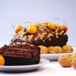 Gros plan d'une tranche de gâteau au chocolat avec des noix et des cerises, parfait pour les amateurs de desserts.