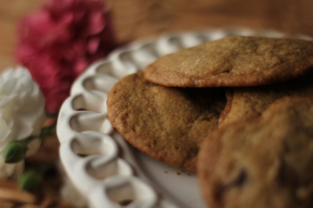 Cookies chauds faits maison sur une assiette décorative avec des accents floraux. Parfait pour les amateurs de gastronomie.