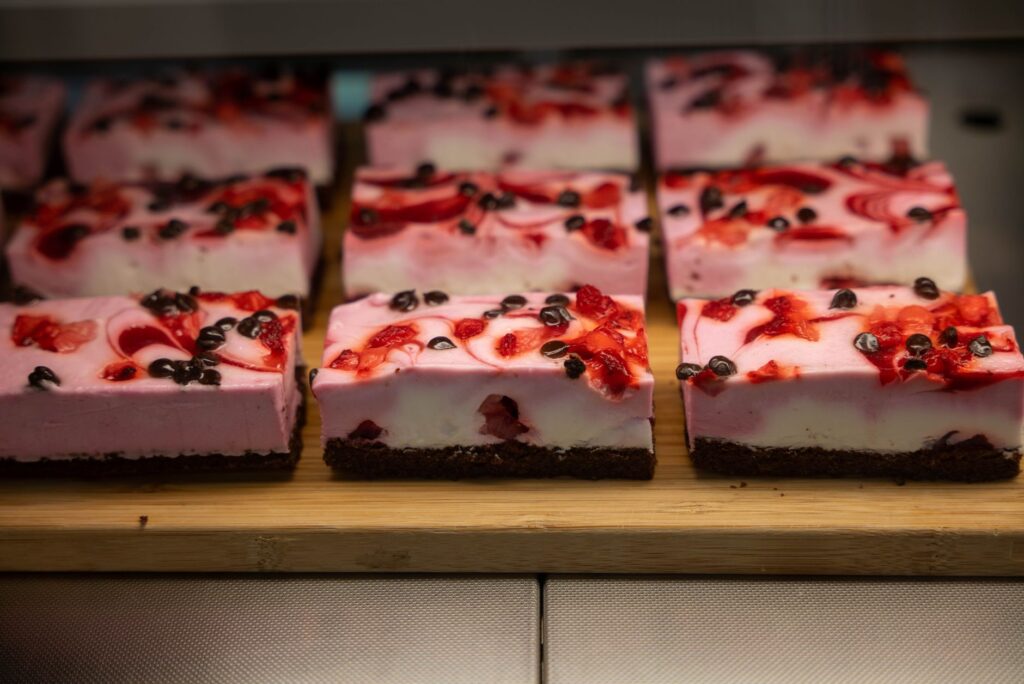 Gâteaux en couches framboise et chocolat tranchés exposés sur une surface en bois dans une boulangerie, Zagreb.