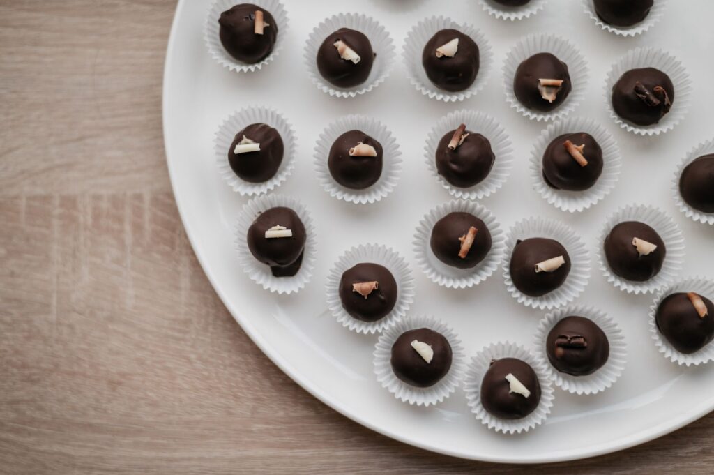Vue de haut de pralinés en chocolat assortis élégamment disposés sur une assiette blanche.