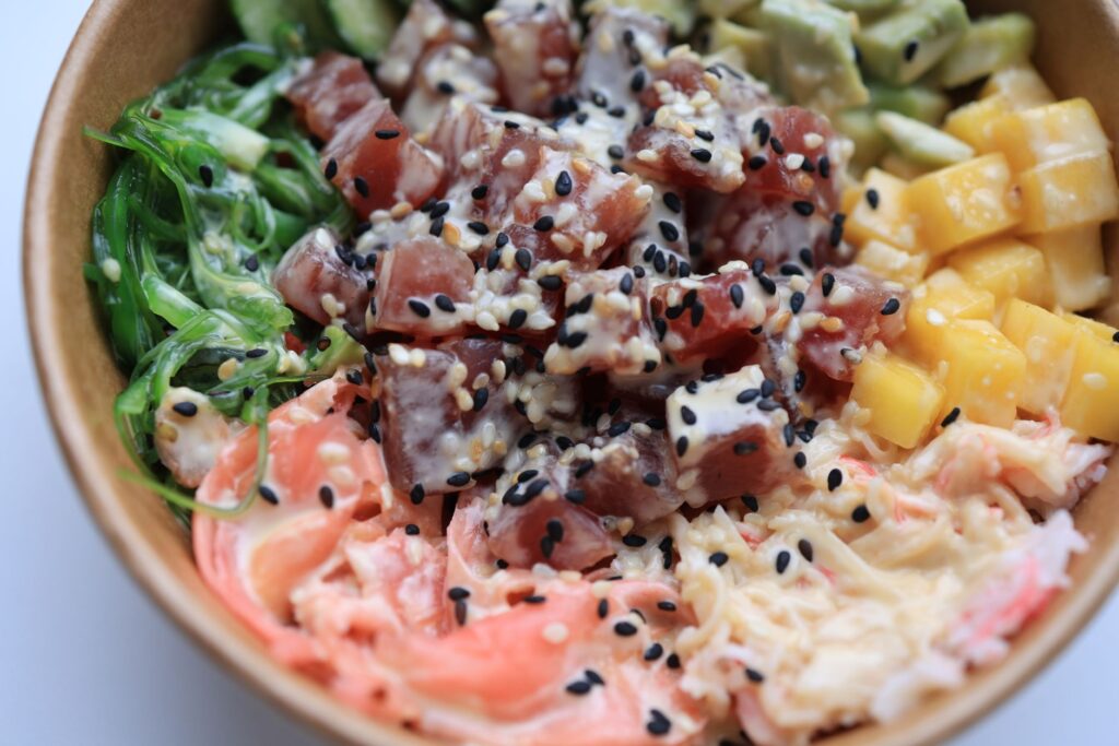 Poke bowl coloré avec du thon, des algues, de la mangue et de l'avocat, décoré de graines de sésame.