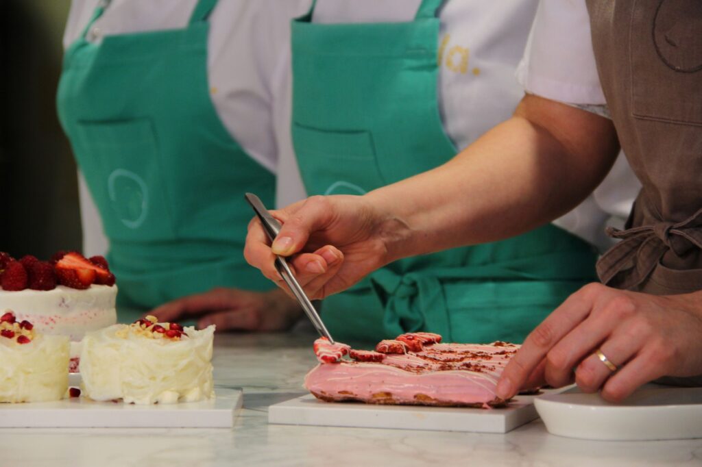 Gros plan de chefs pâtissiers en tabliers décorant méticuleusement des gâteaux gourmets avec précision et art.