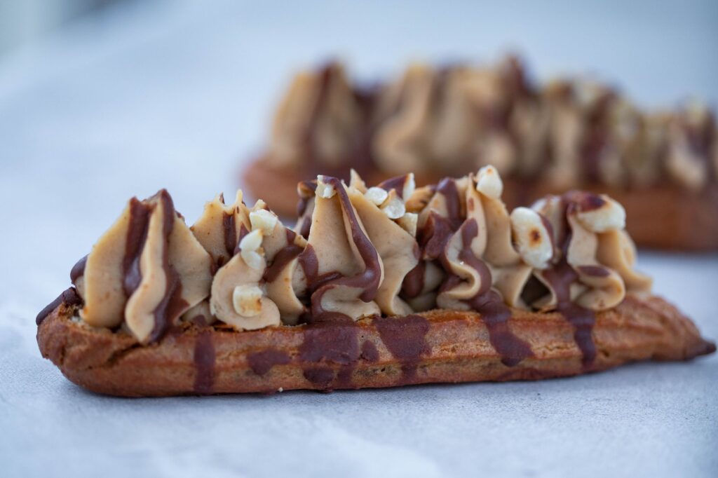 Gros plan sur un délicieux éclair nappé de chocolat et garni de crème, un dessert parfait.