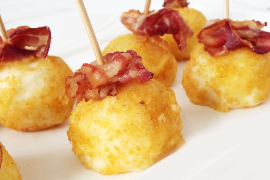 Croquettes de pommes de terre dorées garnies de bacon croustillant, parfaites pour les apéritifs.