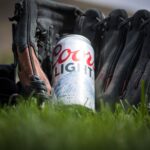 Gros plan d'une canette de Coors Light reposant dans un gant de baseball sur de l'herbe verte fraîche.