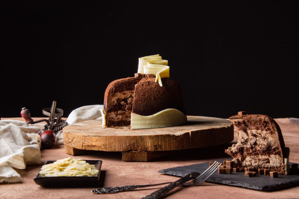 Gâteau au chocolat riche décoré de pépites de chocolat blanc sur une planche en bois rustique.