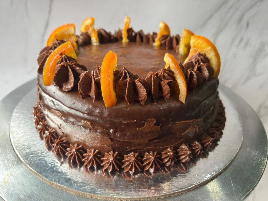 Un gâteau au chocolat riche garni de tranches d'orange et d'un glacage au chocolat.