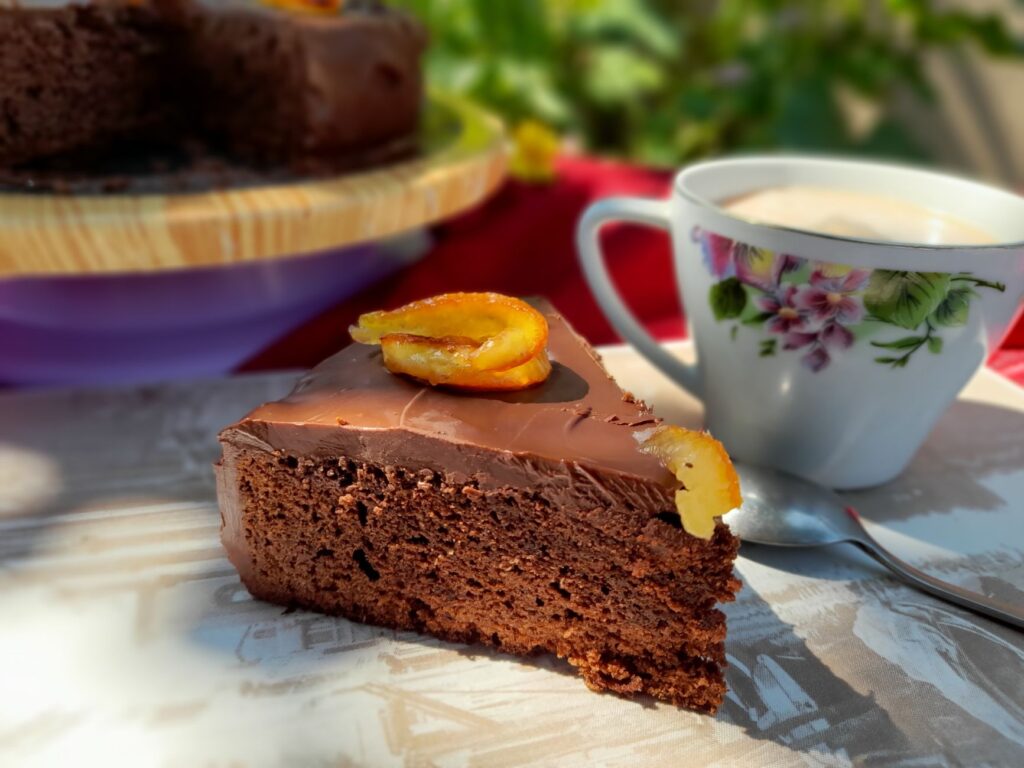 Délicieuse part de gâteau au chocolat garnie d'agrumes, accompagnée de café, idéale pour les amateurs de desserts.