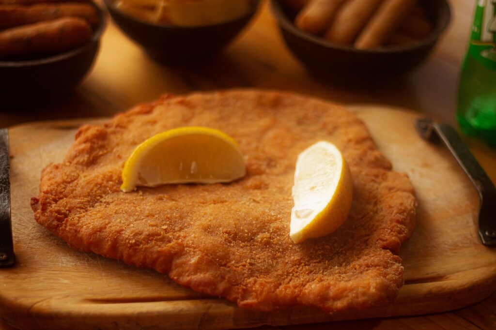 Schnitzel doré servi avec des quartiers de citron sur une planche en bois, parfait pour la photographie culinaire.